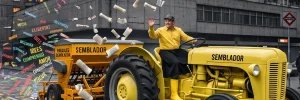 Dans un monde virtuel gris, un homme vêtu de jaune conduit un tracteur-semoir jaune qui sème des mots sur la rue